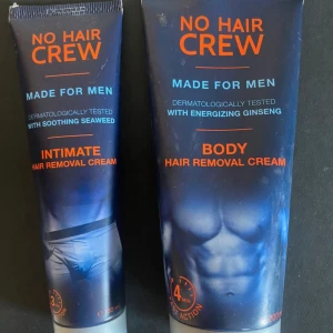No Hair Crew hårborttagningskräm duo - Två tuber hårborttagningskräm för män från No Hair Crew. En för intima områden med lugnande sjögräs (100 ml) och en för kroppen med energigivande ginseng (200 ml). Mörkblå tuber med orange text och bilder av manliga kroppar. Perfekt för enkel och snabb hårborttagning.