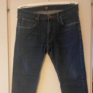 Mörkblå Lee Luke jeans W32 L32 - Bara provade, i nyskick Nypris Carlings 1199 kr, Pris nu 200 kr (Om färgen ser blekare ut på någon bild är det pga fotoljuset, finns inget att anmärka på)  Lee Luke Jeans är slim fit med mid waist och smalare passform runt benen. Ger rörelsefrihet och extra ”pep in your step”. Perfekt som office jeans!  Färg: True Authentic  Style-ID:  l719gcby  Slim fit Avsmalnande ben Bomullsblandning Denim Stretch 5 fickor Mid waist Normal längd Logo-patch 93% Bomull, 5% Polyester, 2% Elastan Maskintvätt 30c