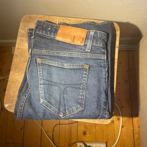 Mörkblå jeans från T/J - Snygga mörkblå jeans från Tiger of Sweden med klassisk femficksdesign och kontrastsömmar. Jeansen har en läderpatch med logga bak i midjan och är tillverkade i slitstarkt denim. Perfekta för dig som gillar en enkel och stilren look.