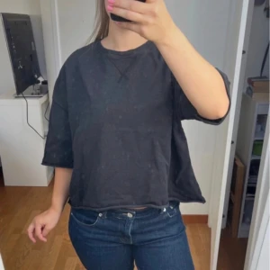 Oversized svart tröja från Zara - Svart oversized tröja från Zara med kortare, bred passform och ribbad rund halsringning. Tröjan har halvkort ärm och är tillverkad i mjuk bomull, perfekt för en avslappnad look. Snygg att styla med jeans eller kjol.