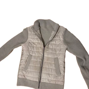 Beige quiltad jacka med stickade ärmar - Säljer en snygg beige jacka med quiltad front och stickade ärmar. Jackan har en dragkedja framtill och ribbade muddar vid ärmslut och nederkant litet slitage på framsidan av jackan och lite små fläckar men de syns knappt vid användning. Storlek L italiensk storlek men sitter som M,Perfekt för våren/vintern! Priset kan självklart diskuteras!🙌