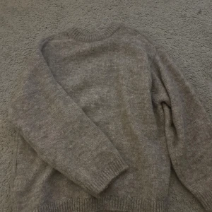 Beige stickad tröja från Gina Tricot - Mysig beige stickad tröja från Gina Tricot med rund halsringning och ribbade muddar vid ärmslut och nederkant. Storlek S.