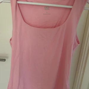 Rosa linnetopp från 157 - Säljer en ljusrosa linnetopp från 157 med rundad halsringning och figurnära passform. Toppen är ärmlös och tillverkad i mjuk bomull. Enkel och stilren design som är lätt att matcha med olika outfits. Aldrig använd bara provat.