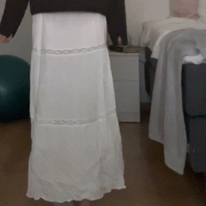 Vit långkjol med spets  - Vit långkjol från H&M med elastisk midja och fina spetsdetaljer i två våder.Materialet är mjukt och svalt, vilket gör den superbekväm att bära. Skriv vid frågor! 