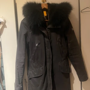  Blonde No.8 jacka - Säljer en svart parkas från Blonde No.8 med stor fluffig päls runt huvan och insidan. Jackan har dragkedja och knappar framtill, två fickor med lock och två med dragkedja. Fodret har ett leopardmönster och päls innanför. Perfekt för kalla dagar! Nästan helt oanvänd, nypris 7000 kr lägger ut för 3000 men pris kan absolut diskuteras 