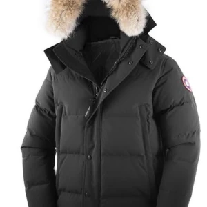 Svart dunjacka Canada Goose med päls - Svart dunjacka från Canada Goose med ikonisk patch på ärmen och fluffig päls runt huvan. Jackan har dragkedja och knappar framtill, långa ärmar med ribbade muddar och flera praktiska fickor. Perfekt för kalla vinterdagar och riktigt snygg streetstil.