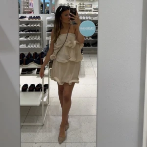 Beige volangset med axelbandslös design - Supersöt beige topp och kjol med volanger och axelbandslös design. Setet har en flowy passform och är tillverkad i ett lätt, plisserat material som ger en luftig känsla. Perfekt för  alla tillfällen och ger en chic vibe. Är i storlek Xs och är i nyskick☺️