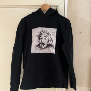 Svart limitato hoodie  - Svart hoodie från Limitato med stor vit patch och konstnärligt tryck på bröstet. Klassisk huva, långa ärmar och diskret Limitato-logga nertill. Mjuk bomullskänsla och relaxed fit – perfekt för dig som gillar streetstyle. Storlek S sitter slim fit riktigt fet 