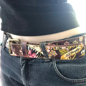 Ed Hardy Bälte - Jättecoolt bälte från ed hardy! Bältets två delar har börjat lossna en del, som syns på sista bilden. Tror det går hur enkelt som helst att limma ihop men det har inte blivit av för mig, så därför säljer jag till någon annan som vill. 109 cm långt.