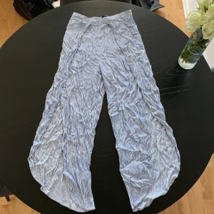 Randiga linnebyxor från KappAhl - Snygga och luftiga linnebyxor från KappAhl i storlek S. Byxorna har ett blåvitt randigt mönster, elastisk midja och ett rakt, lite vidare ben. Perfekta för varma dagar och chill stil. Materialet är mjukt linne som ger en skön känsla.