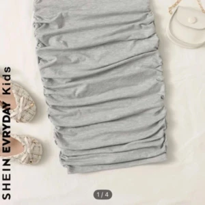 Grå ruched kjol från SHEIN - Snygg grå kortkjol från SHEIN med ruched detaljer längs sidorna. Kjolen har en enkel och stilren look med elastisk midja och är gjord i mjukt bomullsmaterial. Perfekt för dig som gillar en trendig och bekväm stil.