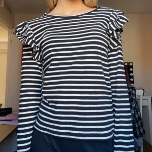 Randig svartvit tröja med volang🖤 - Superfin långärmad tröja från Zara🤍 Tröjan har volangdetaljer på axlarna som ger en extra touch. Mjuk och stretchig, perfekt till jeans eller kjol. Rund halsringning och normal passform.