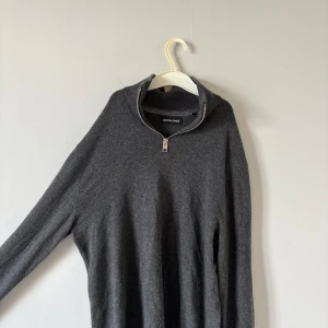 Mörkgrå half zip-tröja Jack & Jones - Mörkgrå stickad  tröja från Jack & Jones med half zip-dragkedja i halsen. Tröjan har en stilren look 