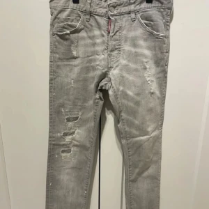 Dsquared2 Cool Guy jeans - Snygga grå Dsquared2 Cool Guy jeans i tvättad look med slitningar och trasiga detaljer framtill och bak. Äkthetsbevis finns! Bara skriv om du vill veta mer.