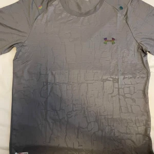 Tränings-tshirt från Under Armour - Helt sprillans ny grå t-shirt från Under Armour.  Tillverkad i lätt och ventilerande polyester, perfekt för träning. Modellen är fitted och har rund hals. Priset gäller endast för tröjan men vill du ha hela setet är d bara och skriva!👌