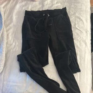 Svarta mjukisbyxor Juicy Couture XXS - Svarta mjukisbyxor från Juicy Couture i storlek XXS. Byxorna har snörning i midjan, fickor fram och broderad JC-logga på ena fickan. Mjukt och skönt material som är perfekt för chill dagar. Klassisk Juicy Couture-look.två hål på fickorna men inget man ser! köpte för 1200 därför säljer för 400