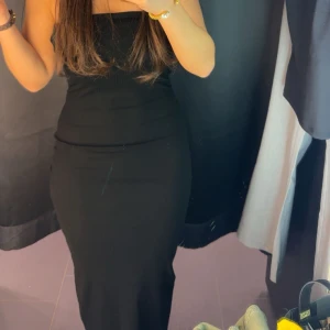 Svart axelbandslös långklänning - Säljer en svart, tight och axelbandslös långklänning med stilren och minimalistisk design. Klänningen har en figurnära passform och är perfekt för dig som gillar en enkel men snygg look. Materialet känns mjukt och följsamt mot kroppen. Har aldrig använt den!! 