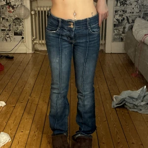 Blå bootcut jeans med dubbla knappar - Säljer ett par blå jeans med bootcut-modell och snygga dubbla knappar i midjan. De är från Bershka och passar 34-36, 150-160cm