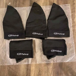 Svart mössa från Kalenji - Svart mössa från Kalenji med stilren design och logga framtill. Mjuk och tunn modell som sitter skönt på huvudet, perfekt för träning eller när du vill hålla dig varm. Materialet är syntet och mössan har en enkel, klassisk form.