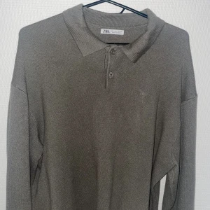 Olivgrön pikétröja från Zara - Snygg olivgrön pikétröja från Zara med klassisk krage och knappar framtill. Tröjan är långärmad och har en stilren, enkel design som passar perfekt till jeans eller chinos. Materialet känns mjukt och lätt mot huden.