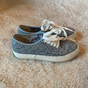 Blå sneakers med blommigt mönster - Snygga blå sneakers med vit sula och vita snören. Skorna har ett broderat blommigt mönster över hela ovandelen och insidan är randig med små röda detaljer. Perfekta för dig som vill ha något unikt och stilrent till vardags.