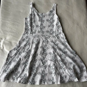 Klänning med blommönster  - Vit ärmlös klänning från Lager 157 med blommönster i storlek 140. Fraktar inom 24h!