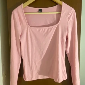Ljusrosa långärmad topp från SHEIN - Säljer en ljusrosa långärmad topp från SHEIN i storlek M. Toppen har en snygg fyrkantig urringning och är figurnära i modellen. Tillverkad i mjuk bomullsmix som känns skön mot huden. Perfekt att styla med jeans eller kjol för en trendig look.
