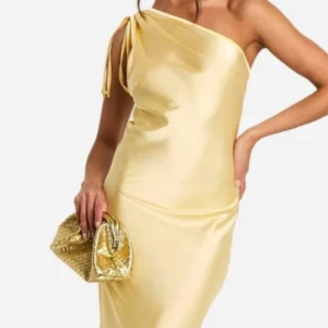 Gul oneshoulder balklänning!! -  långklänning från Boohoo i glansigt satinliknande material. Klänningen har oneshoulder-design med knyt vid axeln och en elegant, figurnära passform.
