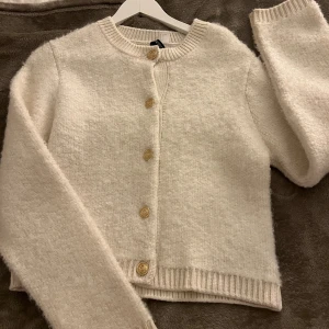 Vit kofta med guldknappar - Stickad kofta från hm i storlek S. Använd nån gång bara, nästan som ny!