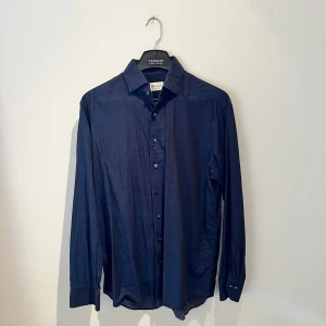 Mörkblå skjorta Stenströms - Snygg mörkblå skjorta från Stenströms med diskret prickigt mönster och klassisk krage. Fitted body-passform och knappar framtill. Perfekt för dig som gillar stilrena detaljer och vill ha en skjorta som sticker ut lite lagom. Hör av er vid frågor 