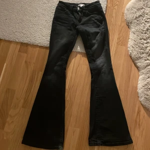 Svarta bootcut jeans Gina Tricot XS - Svarta bootcut jeans från Gina Tricot i storlek XS. Byxorna har snygga nitar på bakfickorna och klassisk femficksdesign. Materialet är stretchigt och bekvämt, perfekt för dig som gillar en trendig siluett med utsvängda ben.