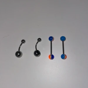Piercingsmycken i silver och blått, (tunga& navel ) - Fyra coola piercingsmycken, två i blankt silverfärgat metall med rundade kulor och två raka stavar med blå och orange kulor. Perfekt för navel eller ögonbryn, ger en färgstark och edgy vibe till din stil.OANVÄNDA!
