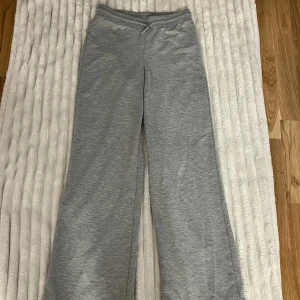 Grå mjukisbyxor med snörning - Säljer ett par grå mjukisbyxor med normal passform och hög midja. Byxorna har raka ben och är tillverkade i mjukt bomullsmaterial. De har en enkel design med snörning i midjan för extra komfort. Perfekta för chill dagar hemma.