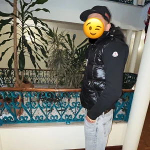 Moncler cardigan  - Säljer en svart, glansig dunväst från Moncler med huva och dragkedja framtill. Västen har Moncler-logga på vänster axel och två sidofickor med dragkedja. Passformen är normal och västen är perfekt för lager-på-lager under kyliga dagar. Lite trasig vid armarna men ingen fara, sömmarna är lite trasiga men de syns knappt
