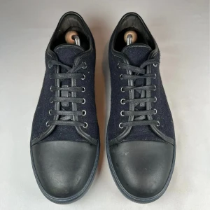 Svarta sneakers från Lanvin - Snygga svarta sneakers från Lanvin. Skorna har rund tå, platt sula och klassisk snörning. Perfekt minimalistisk design med diskreta sömmar och svart yttersula. Enkla att matcha till olika outfits.