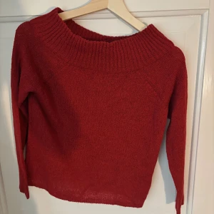 Röd stickad tröja från Amisu - Mysig röd stickad tröja från Amisu med bred ribbad krage och långärmad design. Perfekt för dig som gillar enkel stil med lite extra färg. Tröjan är i storlek XS och har en klassisk passform som funkar till många olika looks.