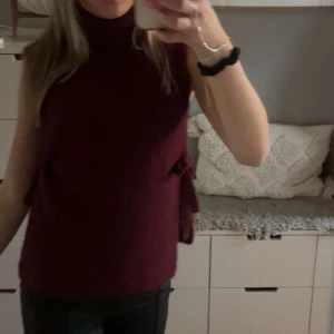 Stickad polotröja med knyt på sidan  - Säljer en vinröd polotröja, som jag har använt en gång. Säljer den för att jag inte tycker den passa så bra på mig den är one size men skulle säga den passar alla. Köpte den för 400