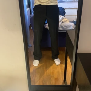 Svarta kostymbyxor med bootcut - Säljer ett par svarta kostymbyxor med en diskret bootcut-snitt och normal passform. Klassisk rak pressveckad look. Perfekta för en clean och stilren outfit.