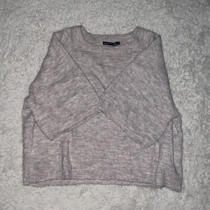 Beige stickad tröja  - Mysig beige stickad tröja med rund halsringning och långa ärmar. Tröjan har en loose passform och ribbade muddar vid ärmslut och nederkant. Perfekt för lager-på-lager under kyliga dagar.