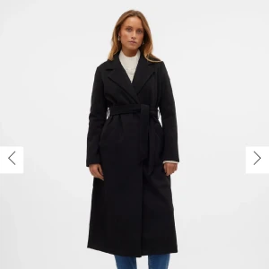 Svart lång kappa med bälte från VeroModa - Säljer en svart, stilren och lång kappa från Vero mosa med klassisk krage och knytbälte i midjan. Kappan har en rak passform, långa ärmar och två sidofickor. Perfekt för dig som gillar minimalistisk och clean stil. Använd en gång. Originalpris: 849kr