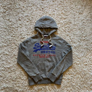 Ljusgrå hoodie från superdry - Snygg grå hoodie från superdry. Använd men i bra skick. Storlek S men tycker den sitter lite större. Tveka inte på o skriva vid fler frågor! 