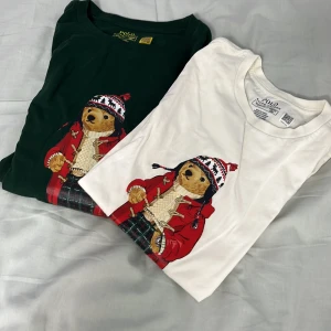 Polo Bear långarmad från Ralph Lauren - Två snygga långarmade från Polo Ralph Lauren med ikoniska Polo Bear-trycket framtill. En i mörkgrönt och en i vitt, båda med björnmotiv i röd jacka och stickad mössa. Klassisk passform och rund hals, tillverkade i mjuk bomull. Skriv om ni vill ha en av tröjorna så sänker jag priset. 
