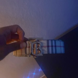 Burberry bälte med guldspänne - Säljer ett Burberry bälte med den klassiska tb bucklen i guld bältet är 110cm. Säljer den billigt pga repor som ni kan se i andra bilden de är inget som märks av på långt håll utan bara om man kollar nära. Priset är inte skrivit i sten, skriv vid funderingar