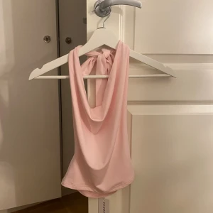 Ljusrosa omlottopp från Venderby's - Supersnygg ljusrosa omlottopp från Venderby's med knyt i nacken och draperad halsringning. Nypris ungefär 370kr och helt oanvänd.