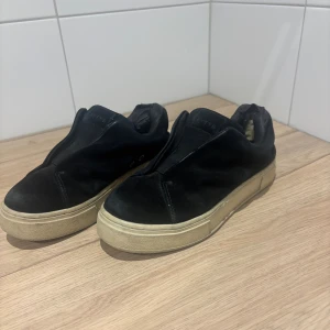 Svarta Eytys sneakers i mocka - Svarta sneakers från Eytys med stilren design och chunky beige platt sula. Ovandelen är i mjuk mocka och har en rund tå. Skorna har en låg profil och saknar synlig snörning för en clean look. Perfekta för dig som gillar minimalistisk streetstyle. Däremot väldigt slitna i hälen