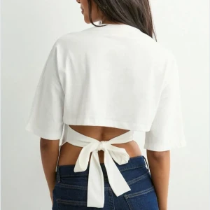 Vit croppad topp med knyt i ryggen - Säljer denna populära toppen från Nelly, en liten fläck där fram som knappt syns❤️