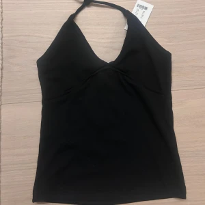 Svart halterneck linnetopp 157 - Säljer då den inte kommmer till användning. Svart halterneck linnetopp från 157 med v-ringning och smala knytband i nacken. Toppen är tight och har en söm under bysten som ger en snygg form. Perfekt till jeans eller kjol för en trendig look. Priset går att buda på❤️