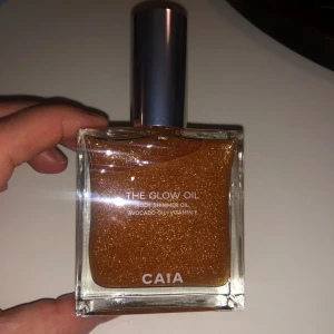 CAIA The Glow Oil Body Shimmer - CAIA The Glow Oil är en lyxig body shimmer-olja med gyllene glitter och skimmer. Innehåller avokadoolja och vitamin E för extra glow. Kommer i en snygg, fyrkantig glasflaska med silverfärgat lock och tillhörande metallic-förpackning.