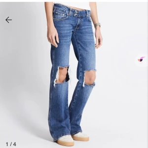 Blå bootcut jeans med hål på knäna - Säljer ett par blå bootcut jeans ifrån lager 157 med stora slitna hål över båda knäna. Jeansen har låg midja, klassiska fem fickor och är tillverkade i jeansmaterial. Passformen är bootcut som släpper vid benen. Knappt använda, storleken är M full length. 