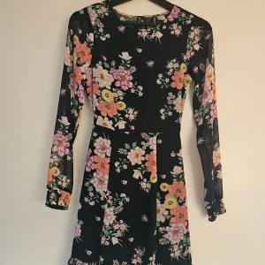 Mörkblå blommig klänning med volang - Superfin mörkblå klänning med blommigt tryck och volanger. Det har en öppen rygg långa tunna armar och fin passform. Kankse ser svårt ut men lovar att den är mörkblå.